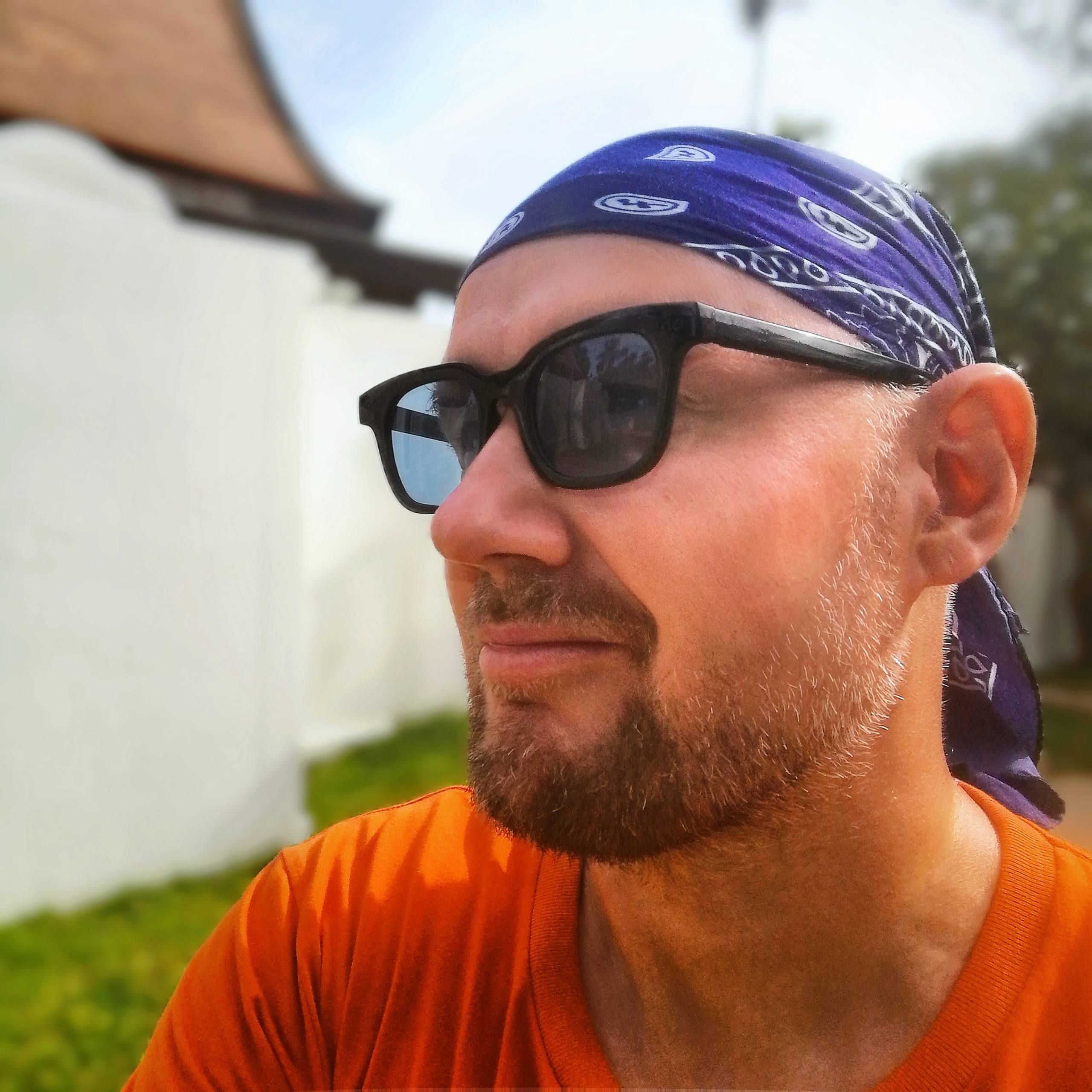 Portrait of Ryan De Vere wearing sunglasses and a purple bandana
